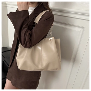 Detail of minimalist beige tote bag showing large capacity and chain shoulder strap