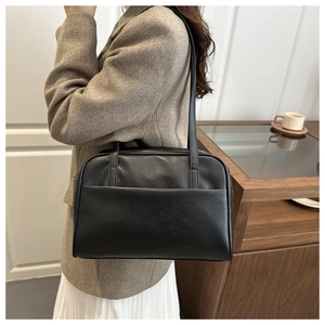 Side view of model wearing a large black leather tote bag with stylish shoulder straps