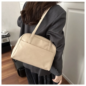 Fashionable cream faux leather tote bag shown on model with dual handles in a modern style
