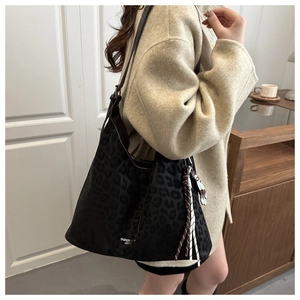 Detail of leopard print tote bag with suede texture and decorative tassel accessory