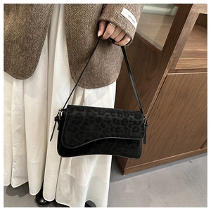 Detail of black leopard print crossbody bag with asymmetric flap and slim strap