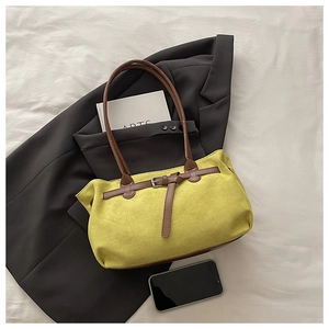 Détail du sac cabas en daim jaune avec anses brunes et boucle argentée sur blazer