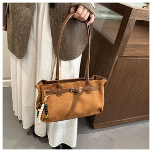 Détail du sac cabas vintage en daim marron avec boucle décorative et gland en perles