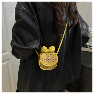 Détail d'un sac jaune à pois avec des marguerites en tissu et un grand nœud décoratif