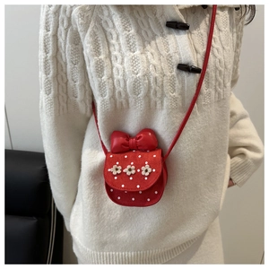 Détail du sac bandoulière rouge à pois avec un grand nœud et fleurs blanches