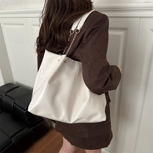 Large cream glossy patent leather tote bag with gold chain strap shown on model