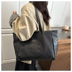 Close-up of black retro tote bag with large embossed circular logo and leather texture