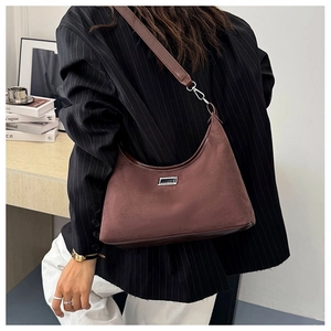 Détail d'un sac porté épaule en daim marron avec ornements argentés sur un bureau