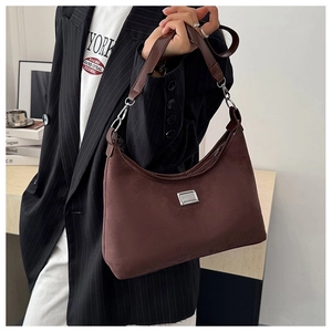 Gros plan d'un sac à bandoulière en daim marron avec plaque argentée et bandoulière