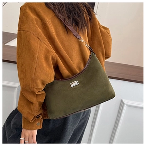Sac bandoulière en daim vert olive avec bordure en cuir marron porté par un mannequin