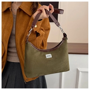 Gros plan d'un sac hobo en daim vert olive avec garniture en cuir marron sur modèle