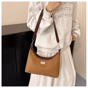 Gros plan du sac porté épaule en daim marron avec bordure en cuir sur un sweat à capuche