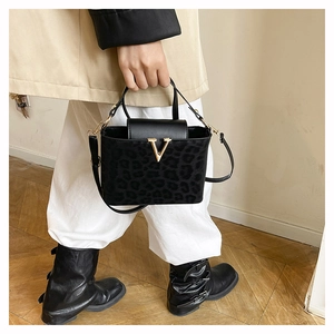 Detail of leopard print handbag featuring a gold V-shaped buckle and textured PU leather