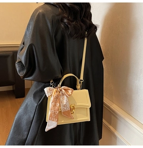 Chic cream small square bag with silk scarf on handle shown from a back view