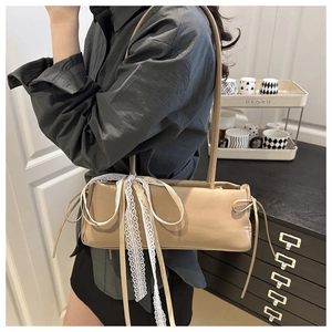 Beige faux leather baguette bag featuring oversized white lace bow with long ribbons