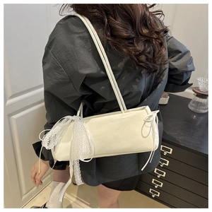 Creamy white leather baguette bag featuring a delicate lace bow and slim double straps