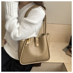 Detail of khaki tote bag with stitching, decorative scarf, and snap button closure