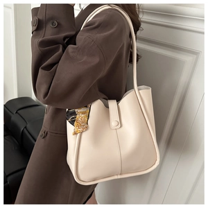 Detail of cream tote bag with patterned silk scarf and slim shoulder strap on leather surface