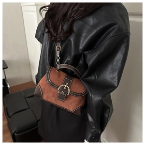 Detail of vintage brown suede shoulder bag with contrast stitching and metal buckle