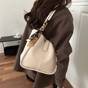Minimalist creamy white leather handbag with silk scarf decoration worn by model