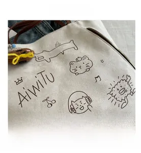 Detail of canvas tote with leather strap, cartoon prints and metal zipper closure