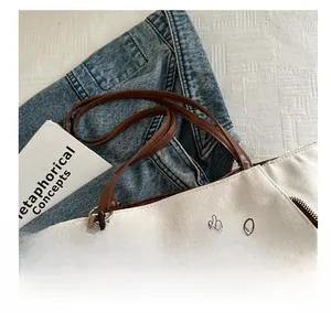 Detail of canvas tote bag with animal line art, brown handle and plush bear charm