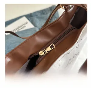 Detail view of smooth golden metal zipper closure on a brown vintage tote bag