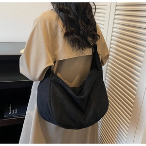 Vue détaillée d'un grand sac hobo noir porté avec un trench-coat beige élégant