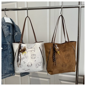 Detail view of retro tote bag showing cartoon print and bear plush charm accessory
