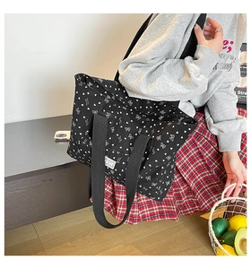 Détail du grand sac cabas en toile noire avec des motifs de cœurs et nœuds blancs