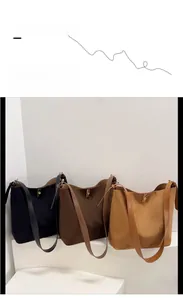 Detailed view of suede bucket bags in black, dark brown, and tan with gold twist locks