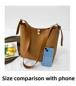 Detail view of large brown suede bucket bag with gold metal buckle and phone size comparison