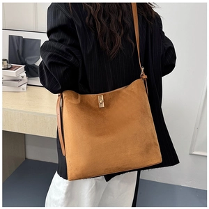 Detail of a brown suede tote bag with a gold metal twist lock and adjustable shoulder strap