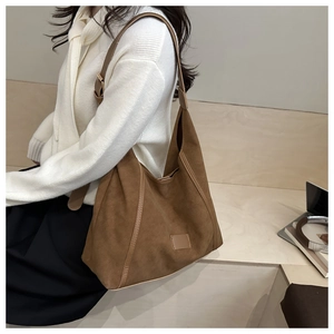 Close-up of brown suede tote bag with leather trim on model in minimalist setting