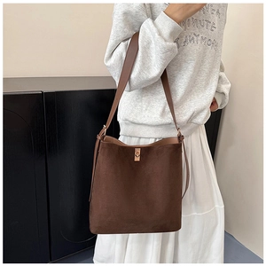 Detail of dark brown suede bucket bag with gold hardware and leather strap