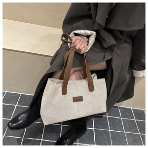 Détail du grand sac cabas en toile crème avec anses et patchs en cuir marron