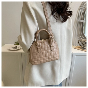 Back view of model wearing a beige crossbody shell bag with embossed plaid pattern