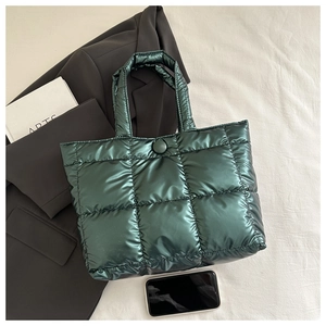 Detail of dark green quilted tote bag showing glossy nylon fabric and size comparison