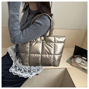 Close-up of quilted champagne gold tote bag with metallic texture and snap closure