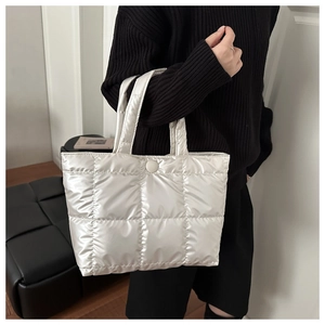 Detail of pearl white quilted puffer tote featuring a magnetic snap closure