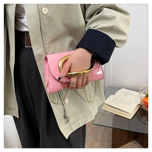 Detail of pink patent leather handbag featuring a stylish large gold metal ring handle