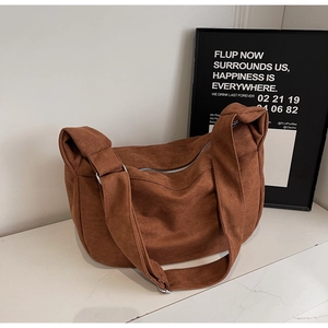 Close-up of caramel brown suede tote bag featuring adjustable strap and metal zipper