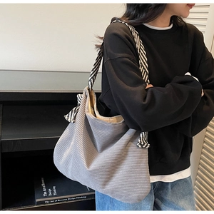 Detail of gray corduroy tote bag with black and white striped tie-knot shoulder strap