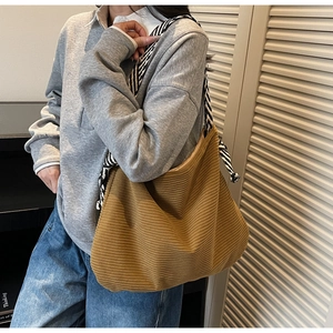 Detailed texture of brown corduroy tote bag with striped woven rope handle