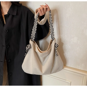Detail of off-white corduroy tote bag featuring thick black and white striped woven straps