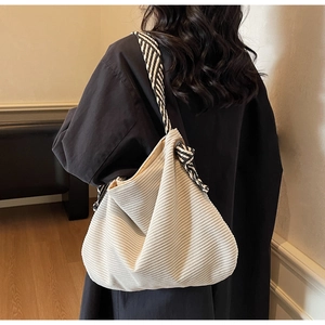 Detail of off-white corduroy tote bag featuring a textured black and white woven strap