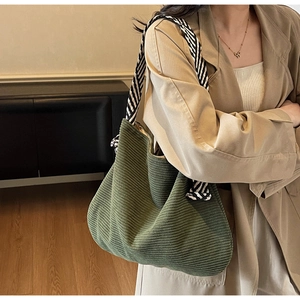 Detail of olive green corduroy tote bag featuring striped fabric knot shoulder straps