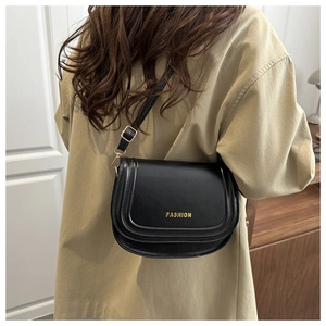 Detailed view of a black leather saddle bag with gold metal buckle and fashion logo