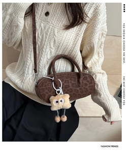 Detail of leopard print suede baguette bag with plush charm and metal zipper accents