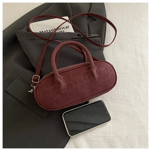 Dettaglio della mini borsa cilindrica bordeaux con morbida texture in pelle scamosciata